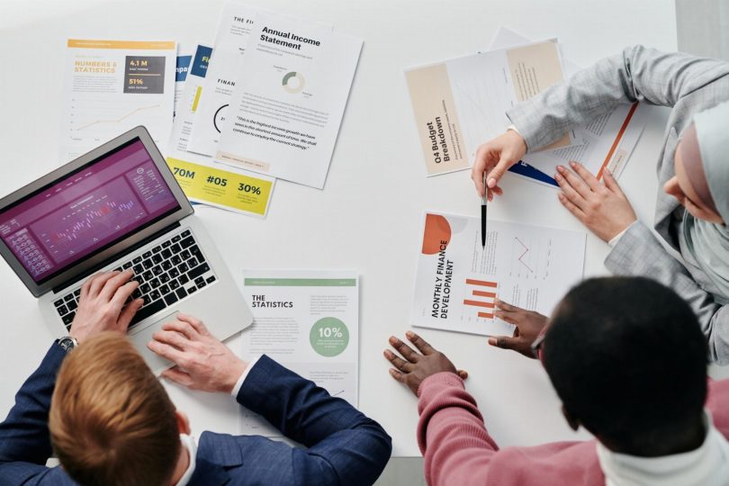 Profissionais do marketing revisando dashboards e relatórios de campanhas online em várias telas