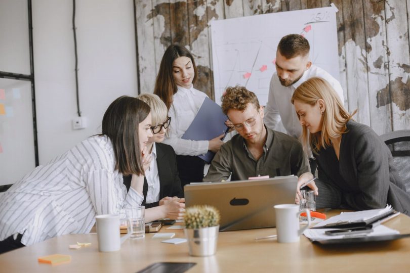 Equipe de pequena empresa desenvolvendo landing page em laptop com anotações
