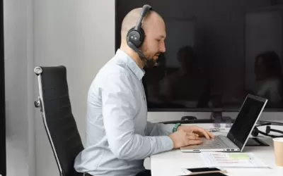 Profissional avaliando desempenho de chatbot em notebook com gráficos de atendimento ao cliente na tela