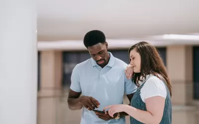 Equipe de pequena empresa reunida em torno de laptop usando assistente de IA para automação de marketing