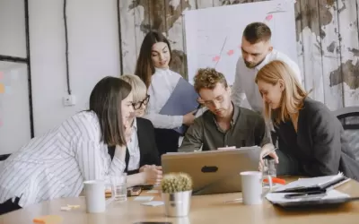 Equipe de pequena empresa desenvolvendo landing page em laptop com anotações