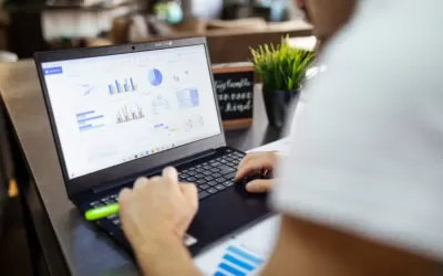 Profissionais analisando relatórios financeiros em laptop com ícone de cadeado representando segurança de dados